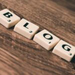 Scrabble tiles spelling 'BLOG' on a wooden background, symbolizing creativity and writing.